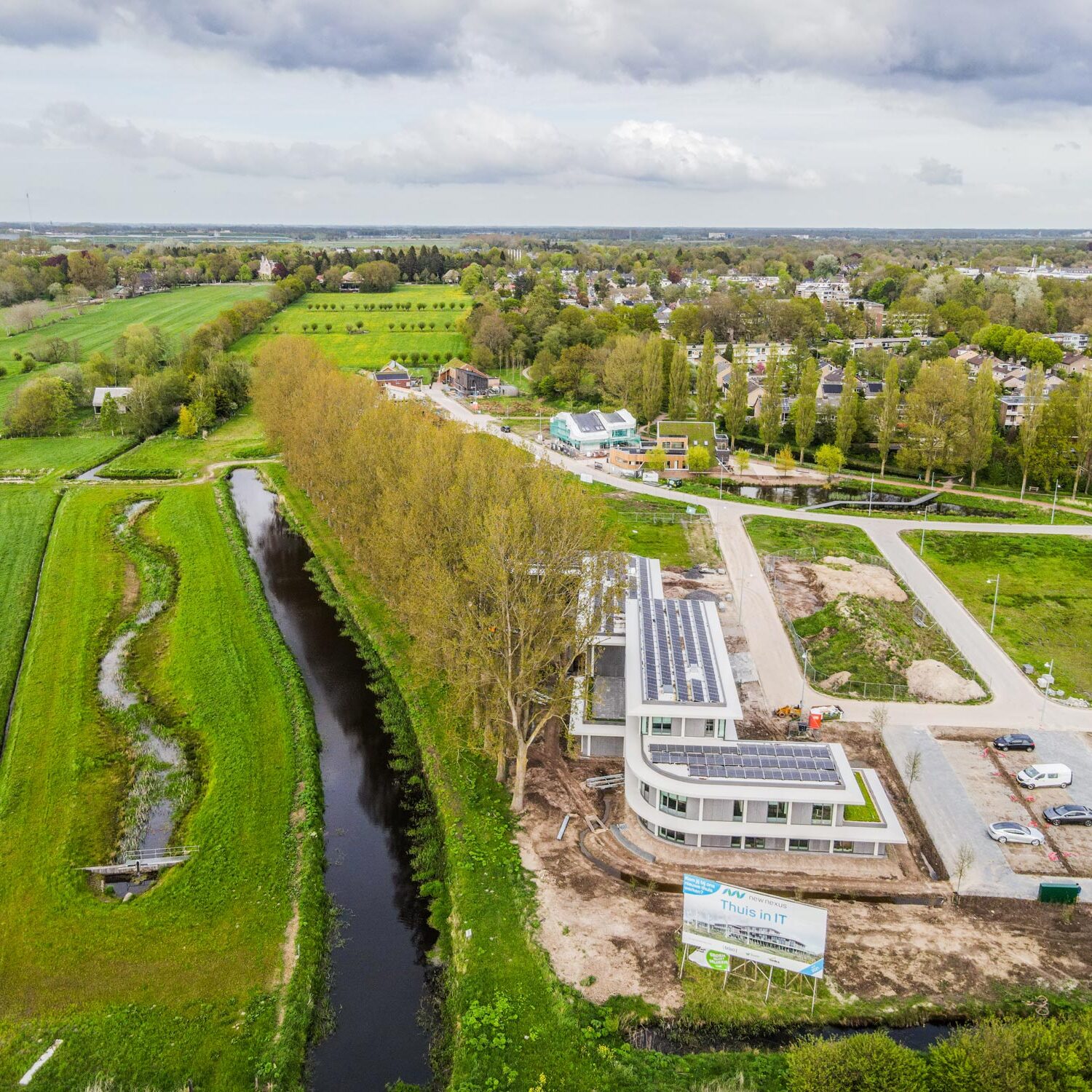 drone beeld van kantoor New Nexus met zonnepanelen in aanbouw in groene omgeving met water