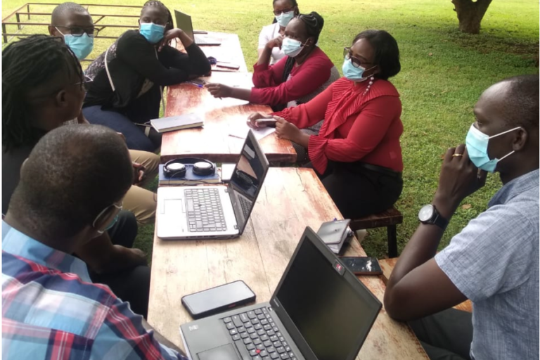 Er vind een overleg plaats aan een lange tafel in de buitenlucht in Afrika