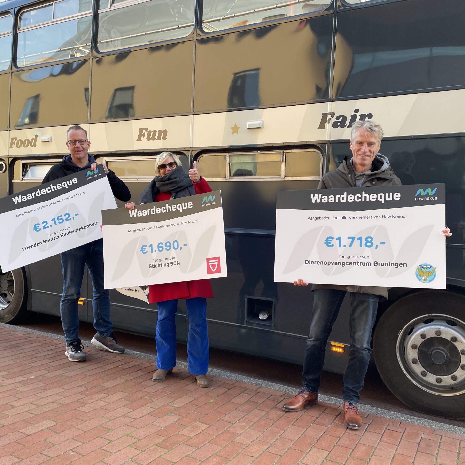 drie medewerkers New Nexus voor de Buster met cheque voor goed doel