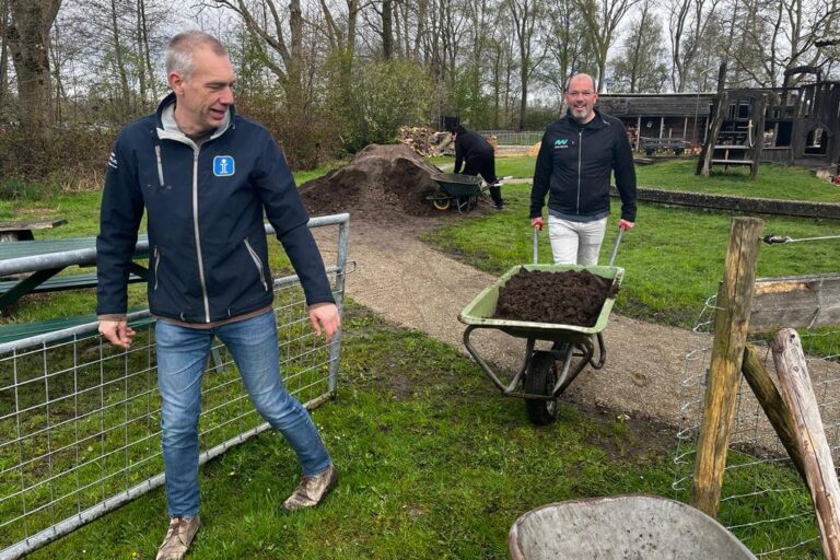 Twee medewerkers van New Nexus helpen met zand verplaatsen tijdens de New Nexus vrijwilligersdag