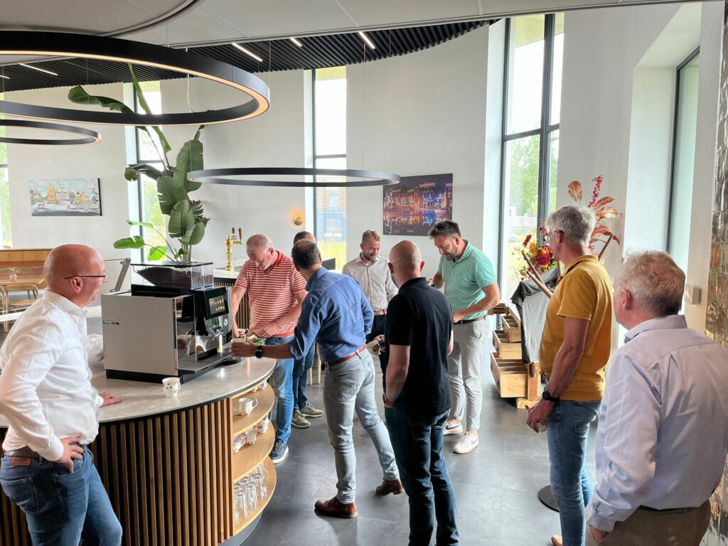 Leden van de NPAL Solution Providers staan te praten bij de koffie in het bedrijfsrestaurant van New Nexus