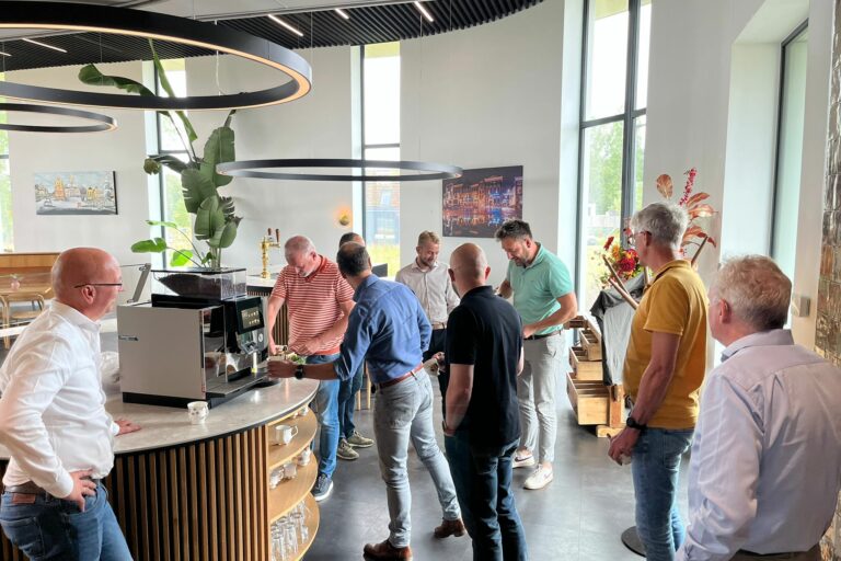 Leden van de NPAL Solution Providers staan te praten bij de koffie in het bedrijfsrestaurant van New Nexus