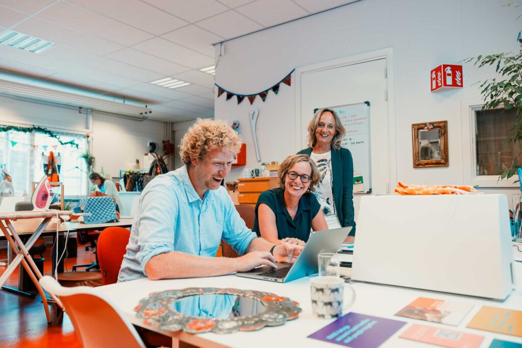 Tim met locatiemanager Nais en directeur WerkPro achter de laptop in het naaiatelier