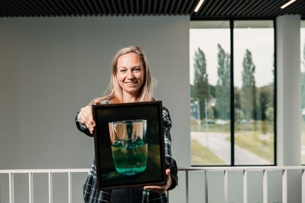Carmen toont een van haar schilderijen die bij New Nexus op kantoor hangen