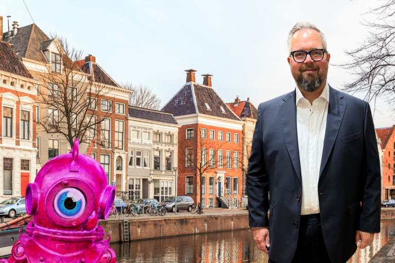 Spreker op aiGrunn Marco Tenback staat samen met roze robot op de kade van de Westerhaven