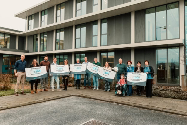 Alle goede doelen met cheque op een rij voor kantoor New Nexus Alle goede doelen met cheque op een rij voor kantoor New Nexus