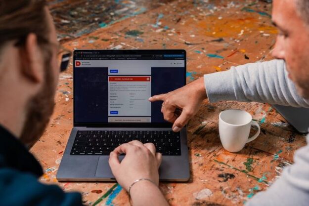 Kijkend en wijzend naar beeldscherm met daarop prototype Sociale Bouwmarkt Kijkend en wijzend naar beeldscherm met daarop prototype Sociale Bouwmarkt