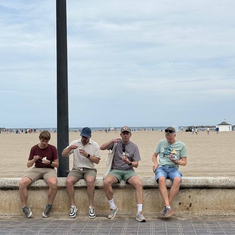 Vier collega's eten ijsje bij strand