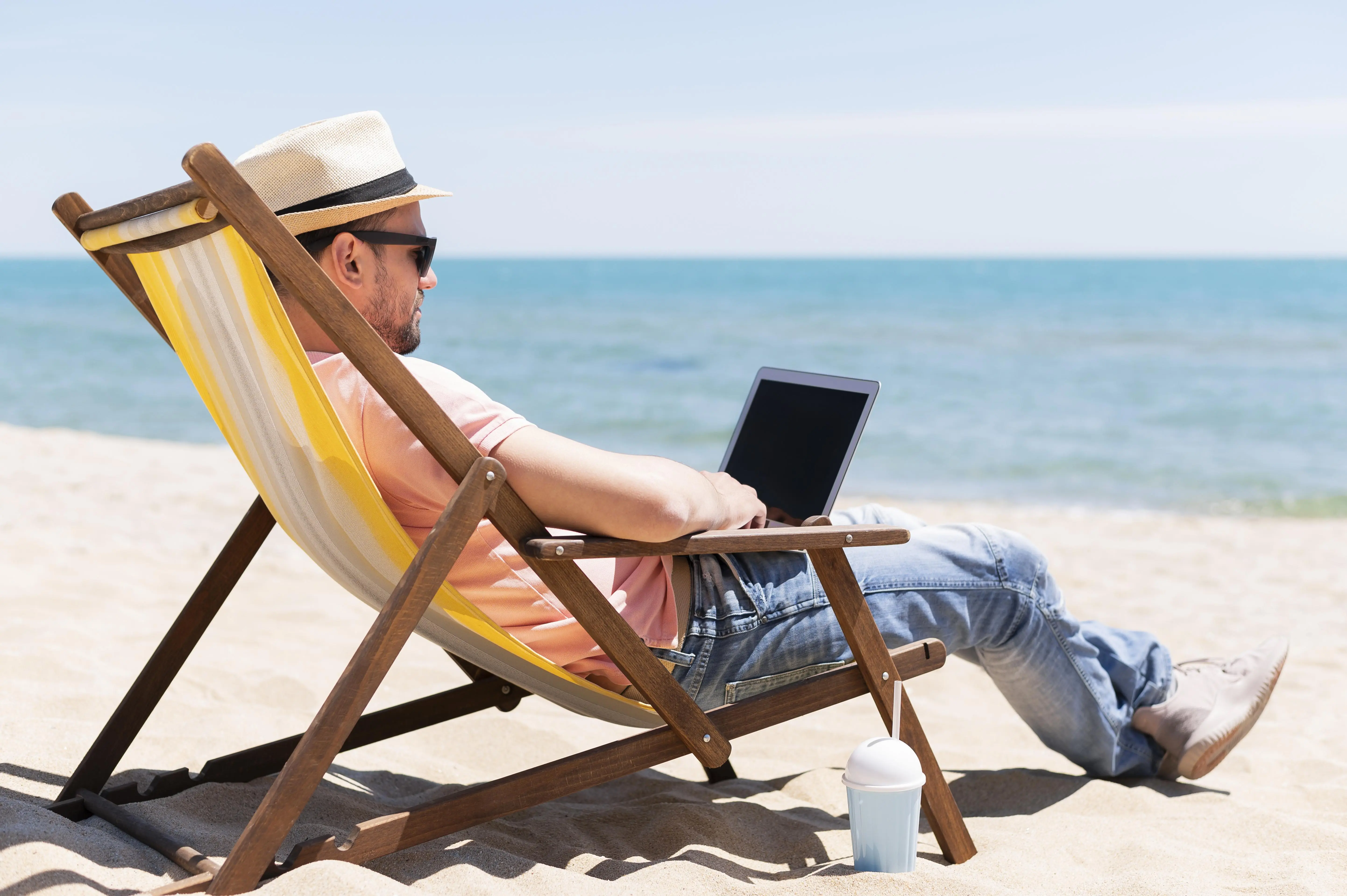 man met laptop in strandstoel
